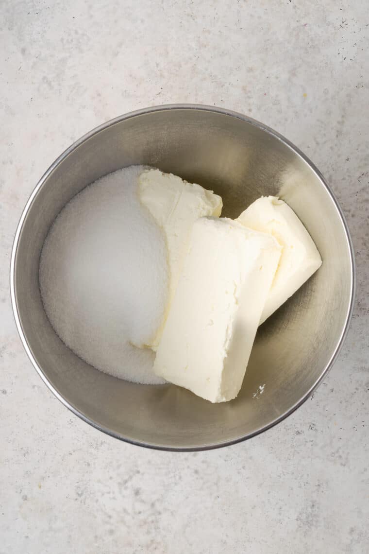 Cream cheese and sugar in a silver bowl.