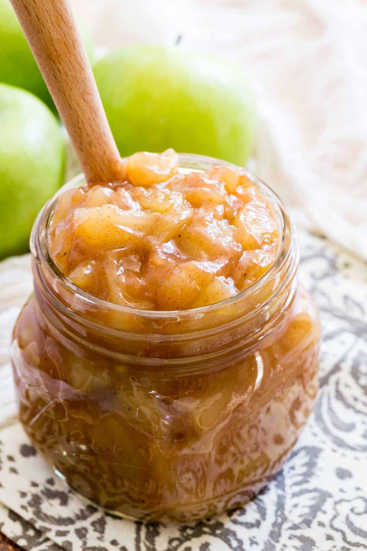 A jar of apple pie filling with a wooden spoon.