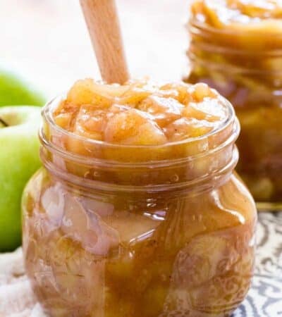 A jar of apple pie filling with a wooden spoon.