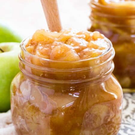 A jar of apple pie filling with a wooden spoon.