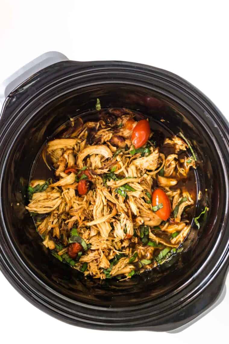 Slow cooker tomato basil chicken in the bowl of the crockpot.