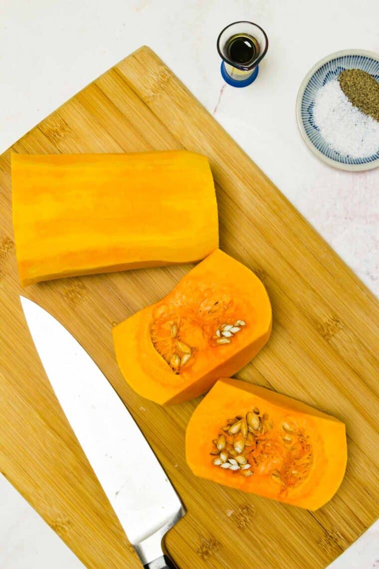A cutting board with cut pieces of butternut squash and a knife.