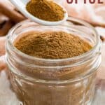 A white spoon of pumpkin spice mix being held over a jar of the blend with text overlay that says "Pumpkin Pie Spice".