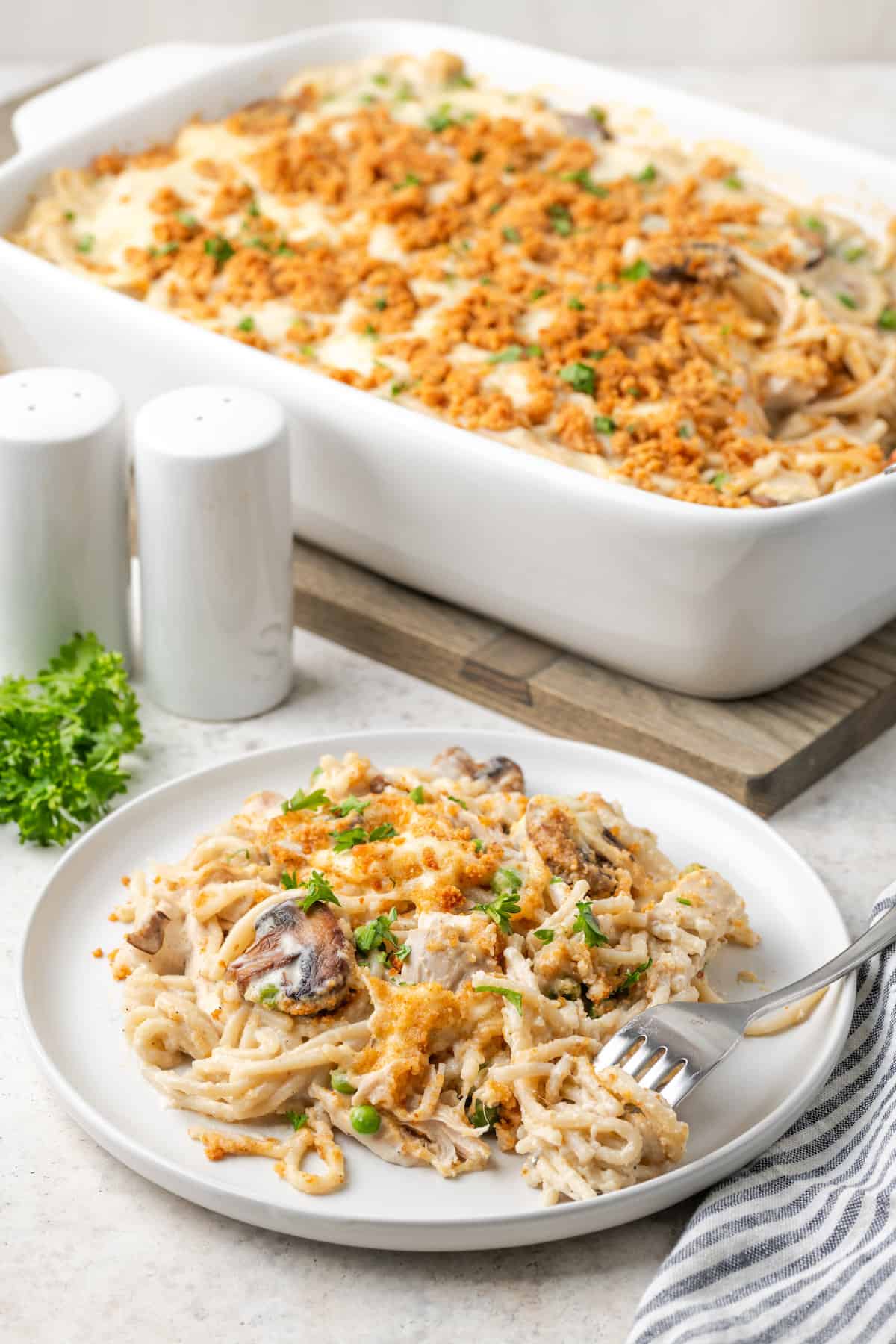 A plate of chicken tetrazzini with a fork with a pan in the background.