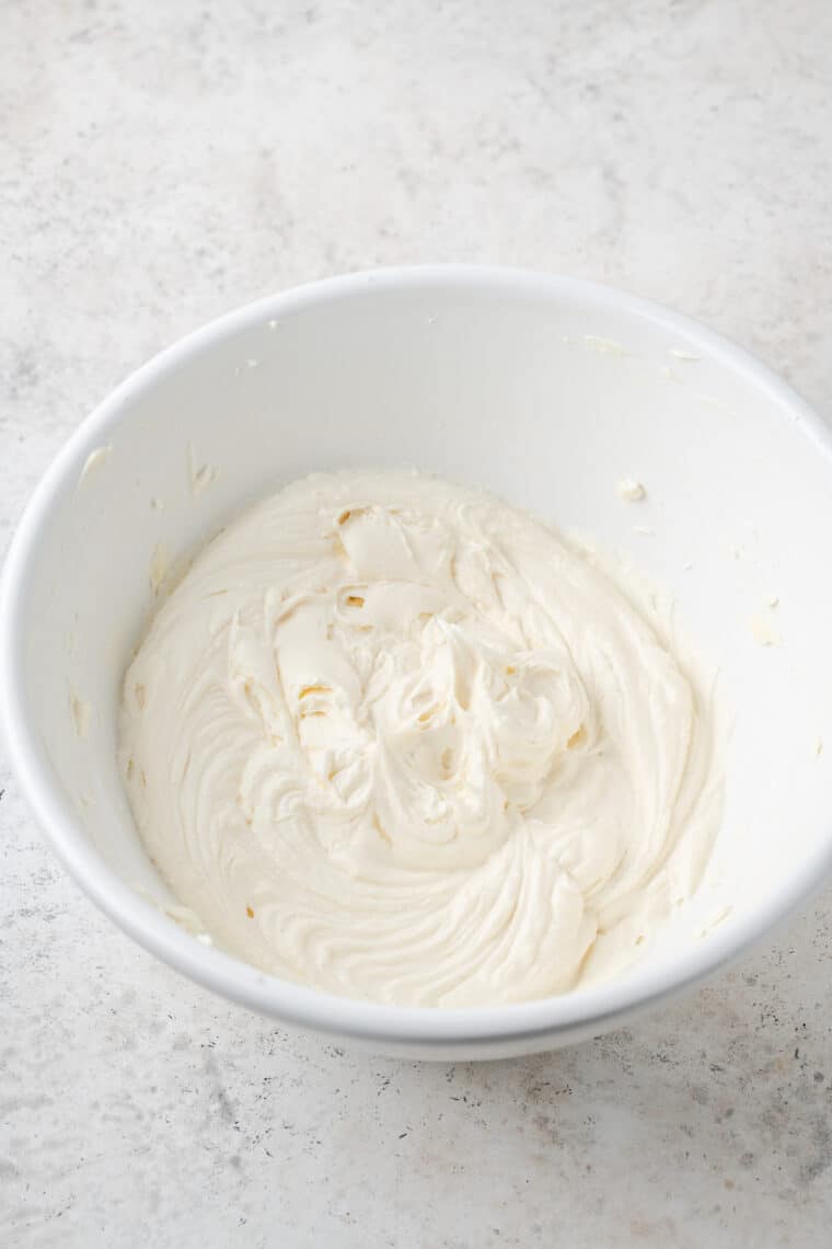This Gluten-Free Pumpkin Roll takes a tender cake and stuffs it with tangy cream cheese frosting for a gorgeous fall dessert. Cream cheese filling in a bowl.