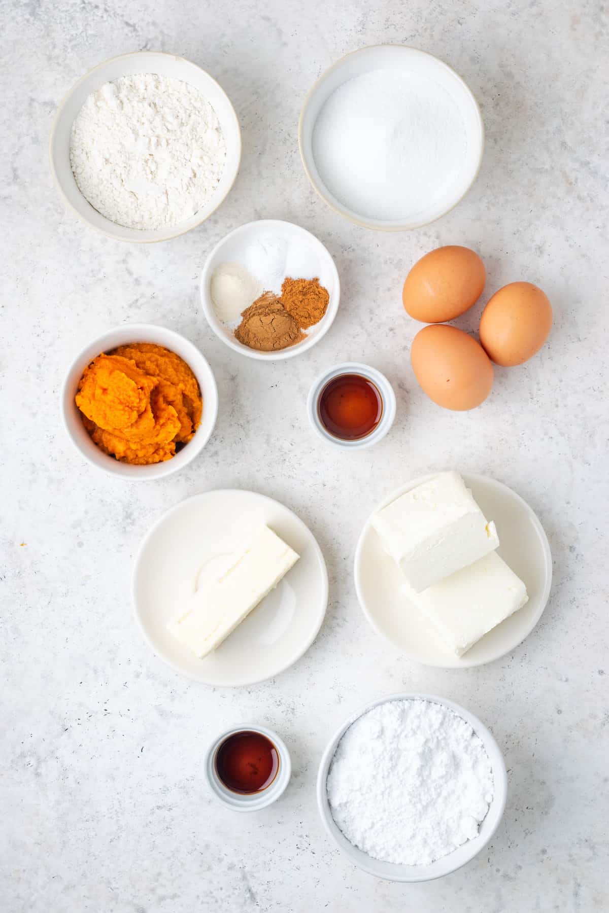 Ingredients for pumpkin roll are shown: eggs, pumpkin puree, cream cheese, butter, sugar, powdered sugar, spices.