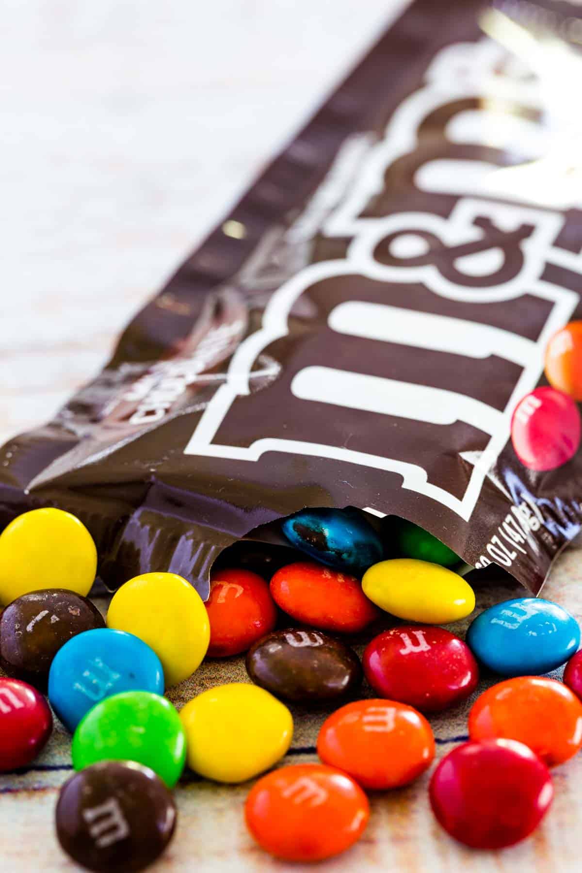 M&M's candies spilling out of a bag of plain M&M's.