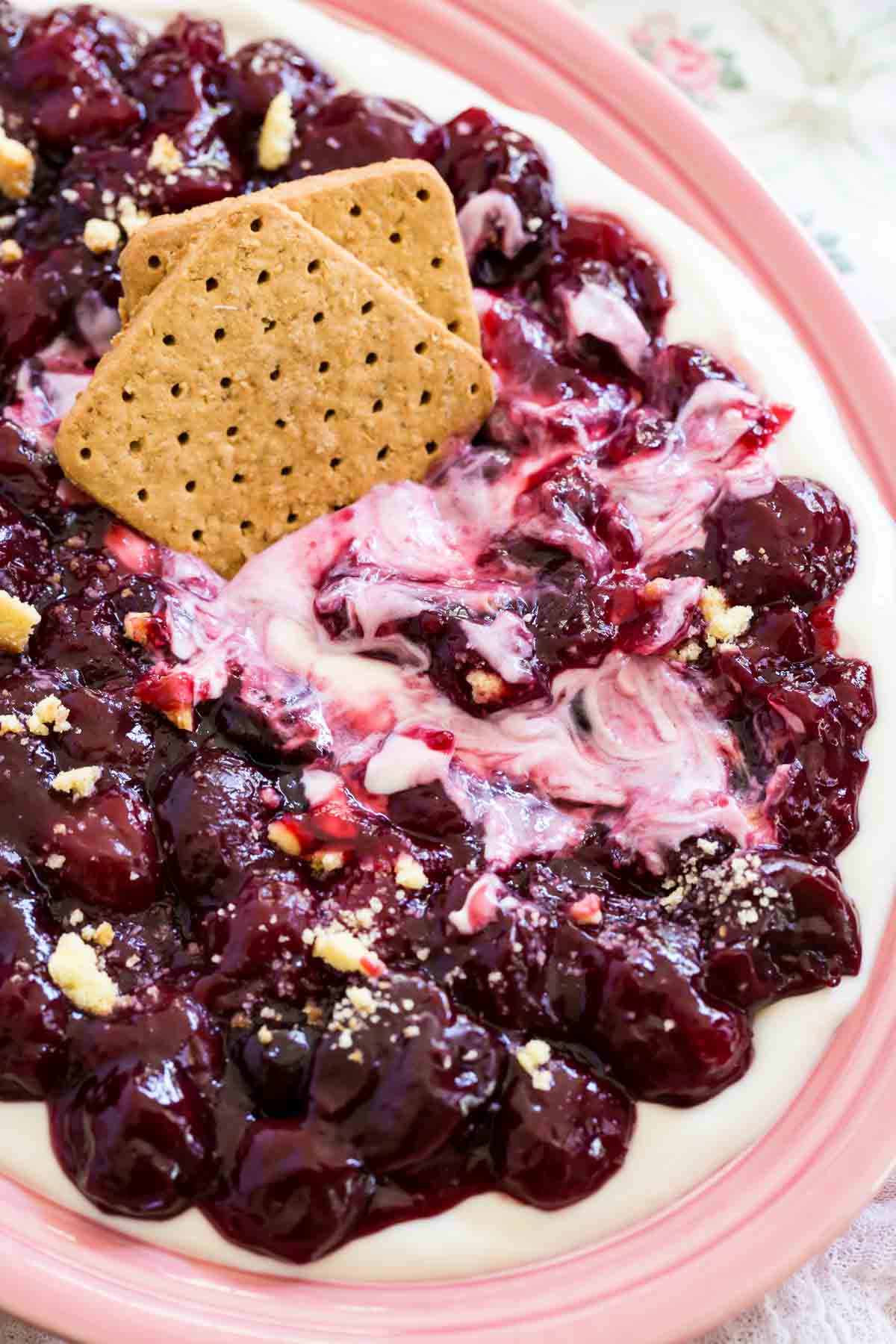 Cookies are shown in a bowl of cherry cheesecake dip.