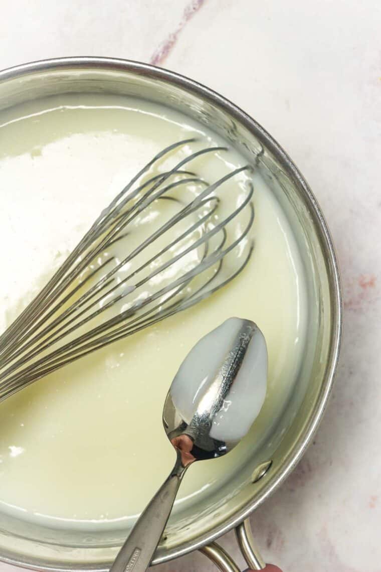 A spoon and a whisk are shown in pan of pudding.