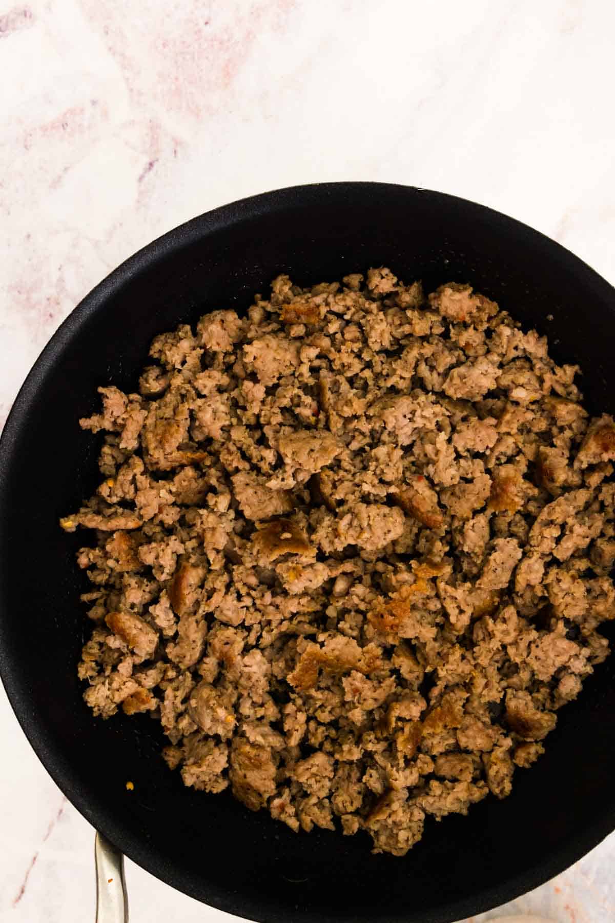 Sausage browns in a cast iron skillet.