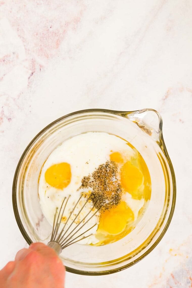 Eggs are whisked with cream, milk, and salt and pepper.