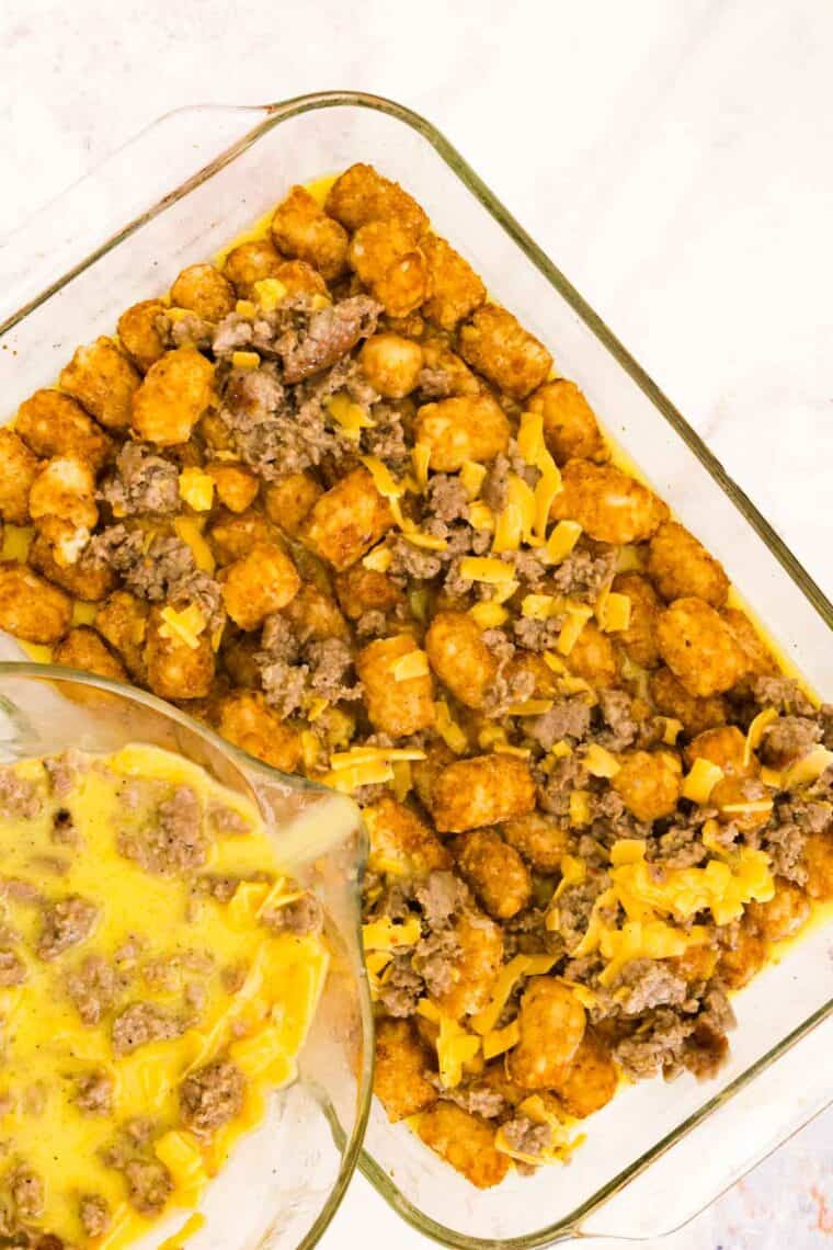 Egg mixture is poured over a pan of tater tots.