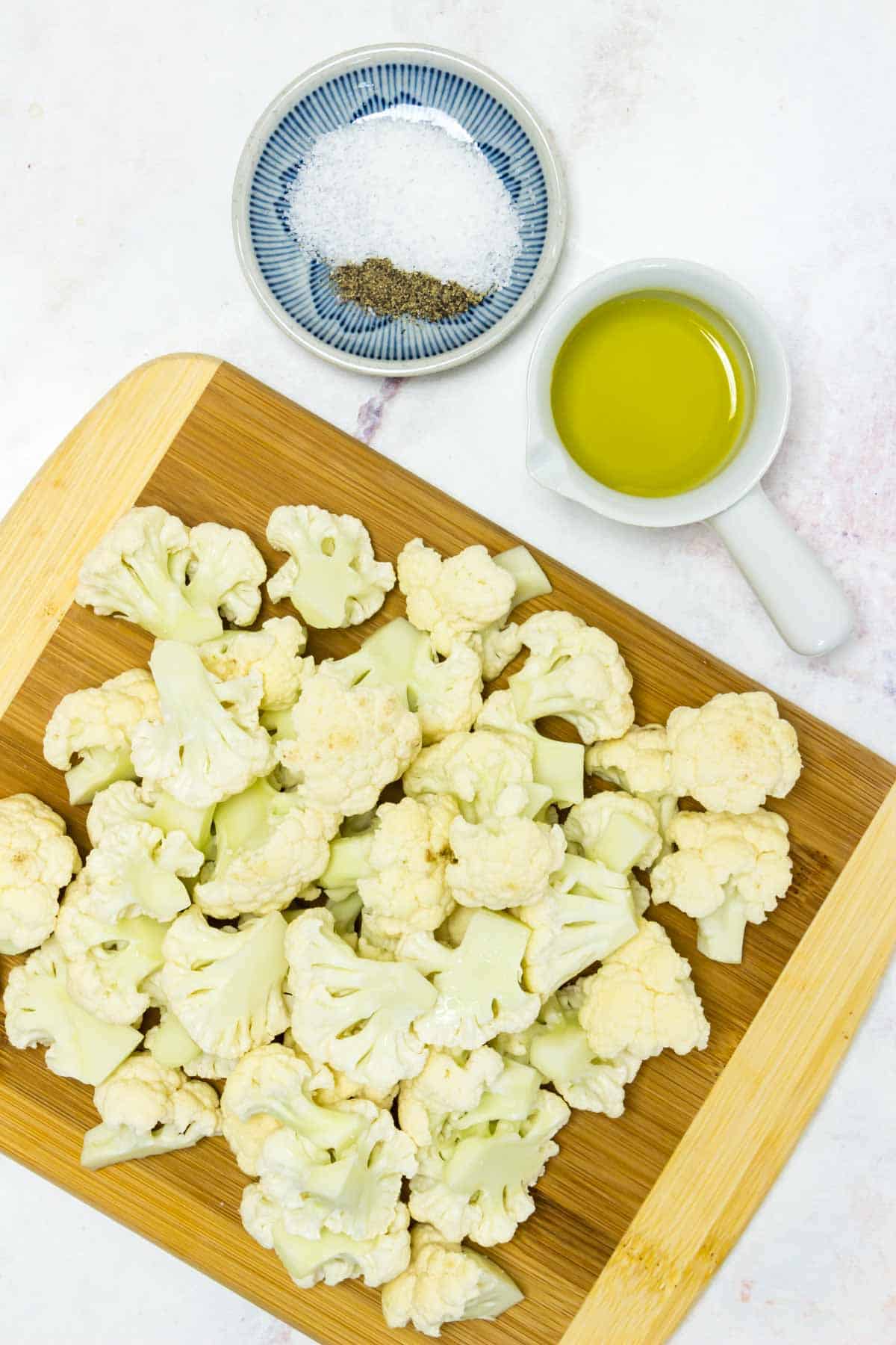 ingredients needed to make roasted cauliflower are shown: cauliflower, olive oil, and salt and pepper.
