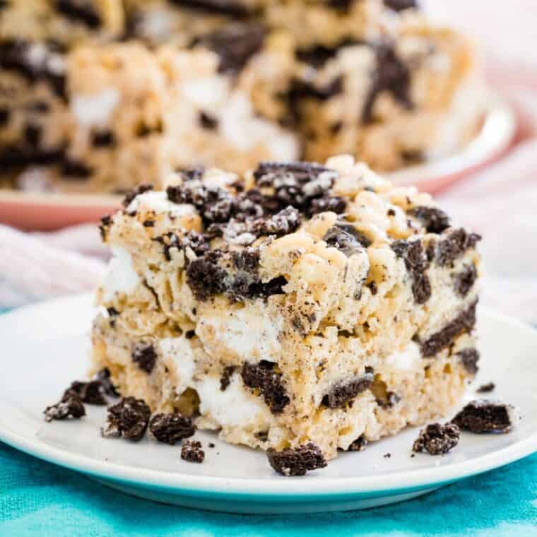 An Oreo Rice Krispies Treat on a small white plate surrounded by Oreo crumbs.