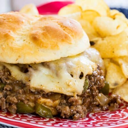 A philly cheesesteak sloppy joe sandwith with the meat filling and cheese overflowing off the bun.