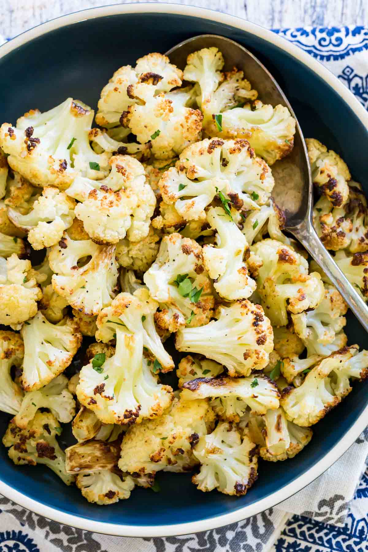 A bowl of roasted cauliflower with a spoon.