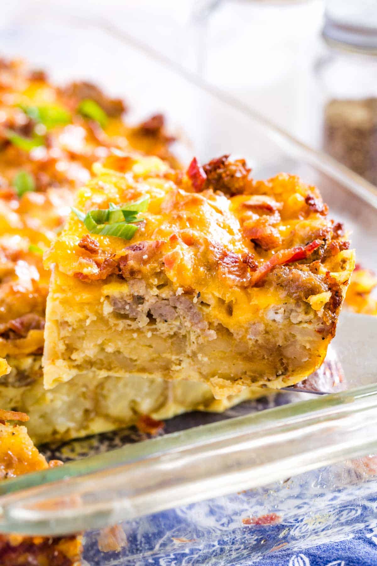A glass baking dish is shown full of tater tot breakfast casserole.