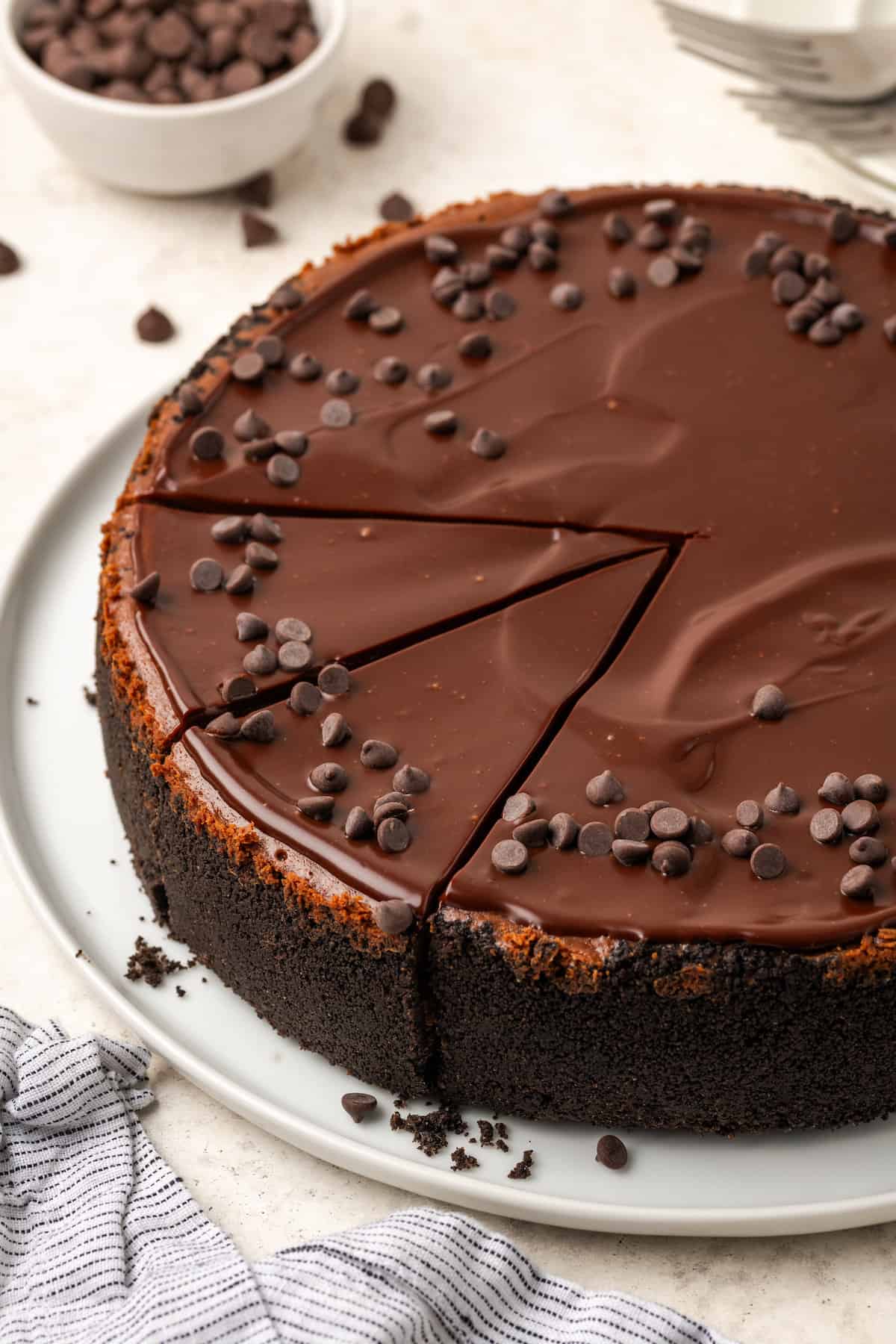Chocolate cheesecake is shown topped with ganache and chocolate chips.