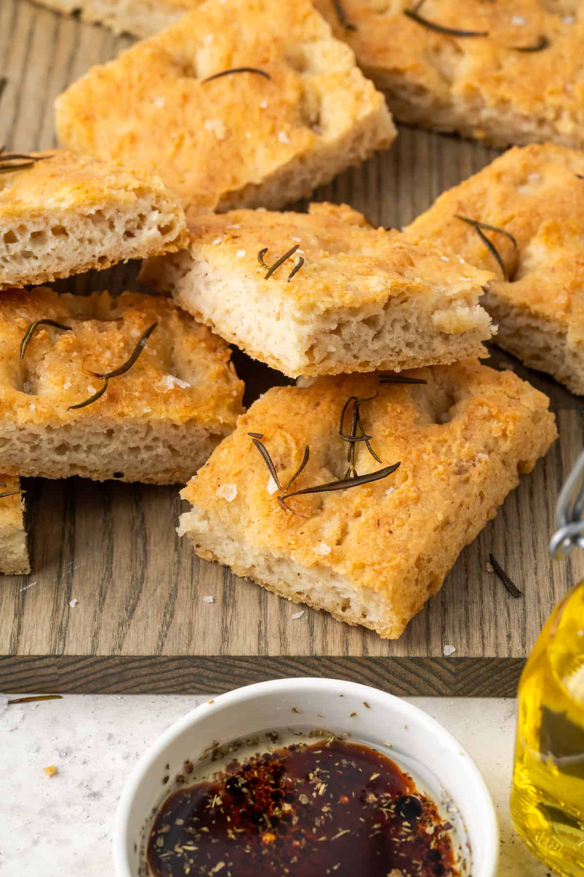 Pieces of gluten free focaccia is shown on a cutting board.