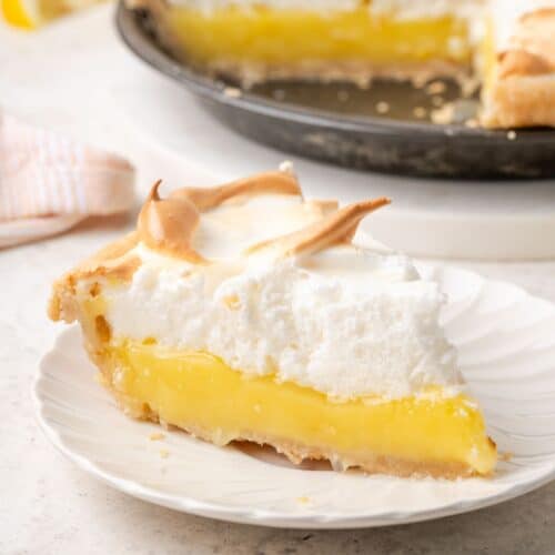 A slice of lemon meringue pie on a white plte.