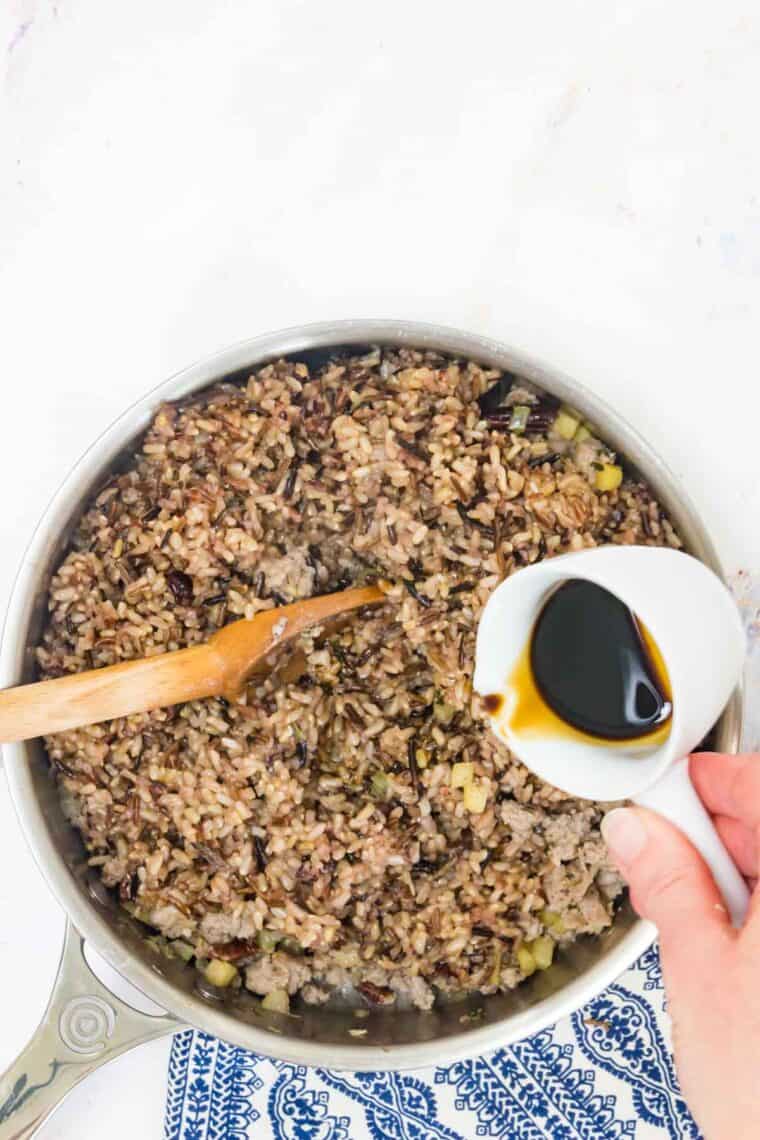 Balsamic vinegar is poured into a skillet of wild rice stuffing.