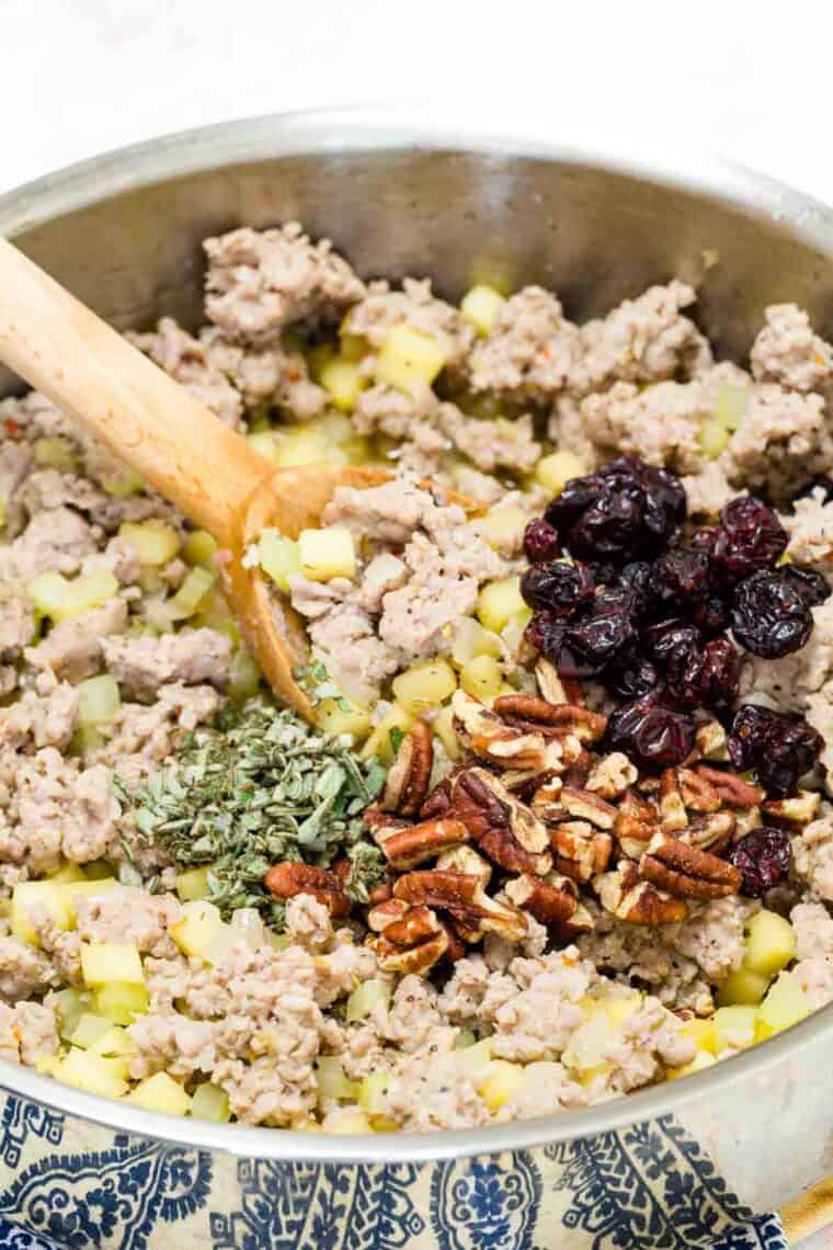 A wooden spoon stirs a skillet of wild rice stuffing.