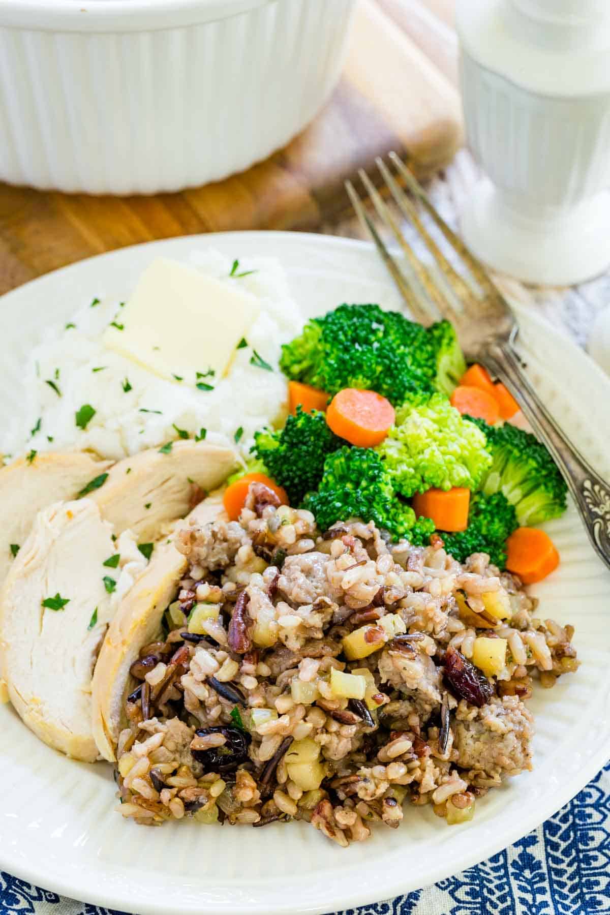 A white plate of wild rice stuffing and vegetables.