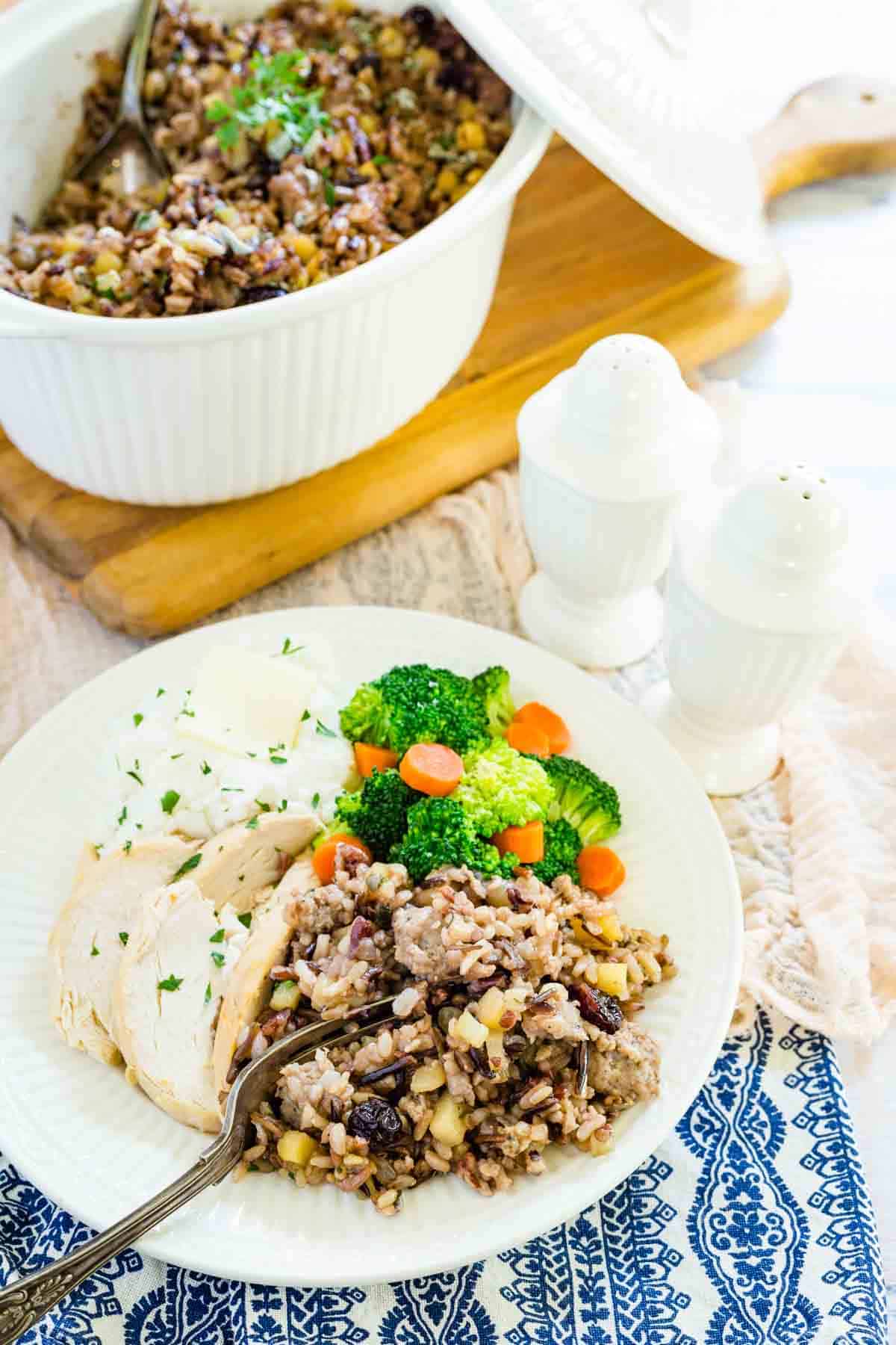 A white plate of wild rice stuffing and vegetables.