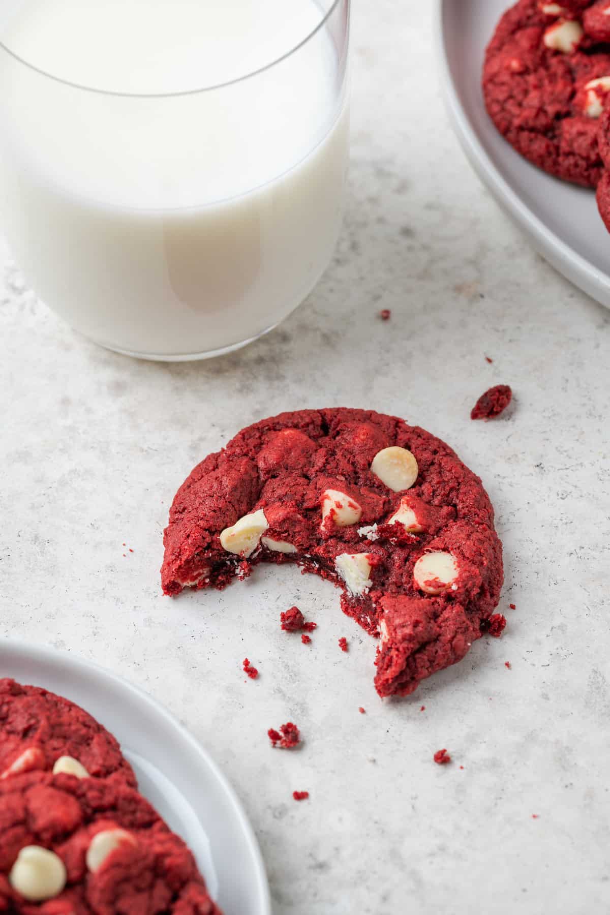 A red velvet cookie with a glass of milk on a white background.