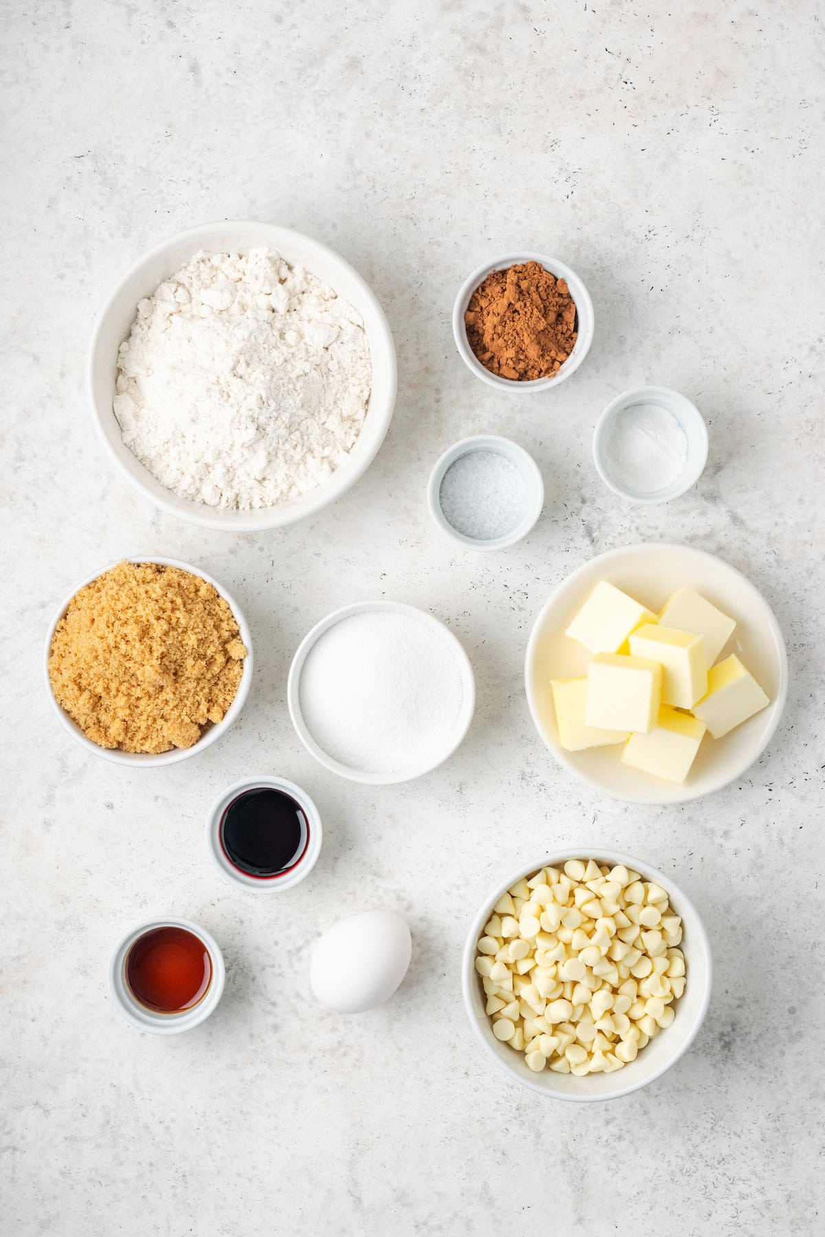 Ingredients needed to make red velvet cookies are shown: butter, brown sugar, granulated sugar, egg, white chocolate chips, gluten free flour mix.