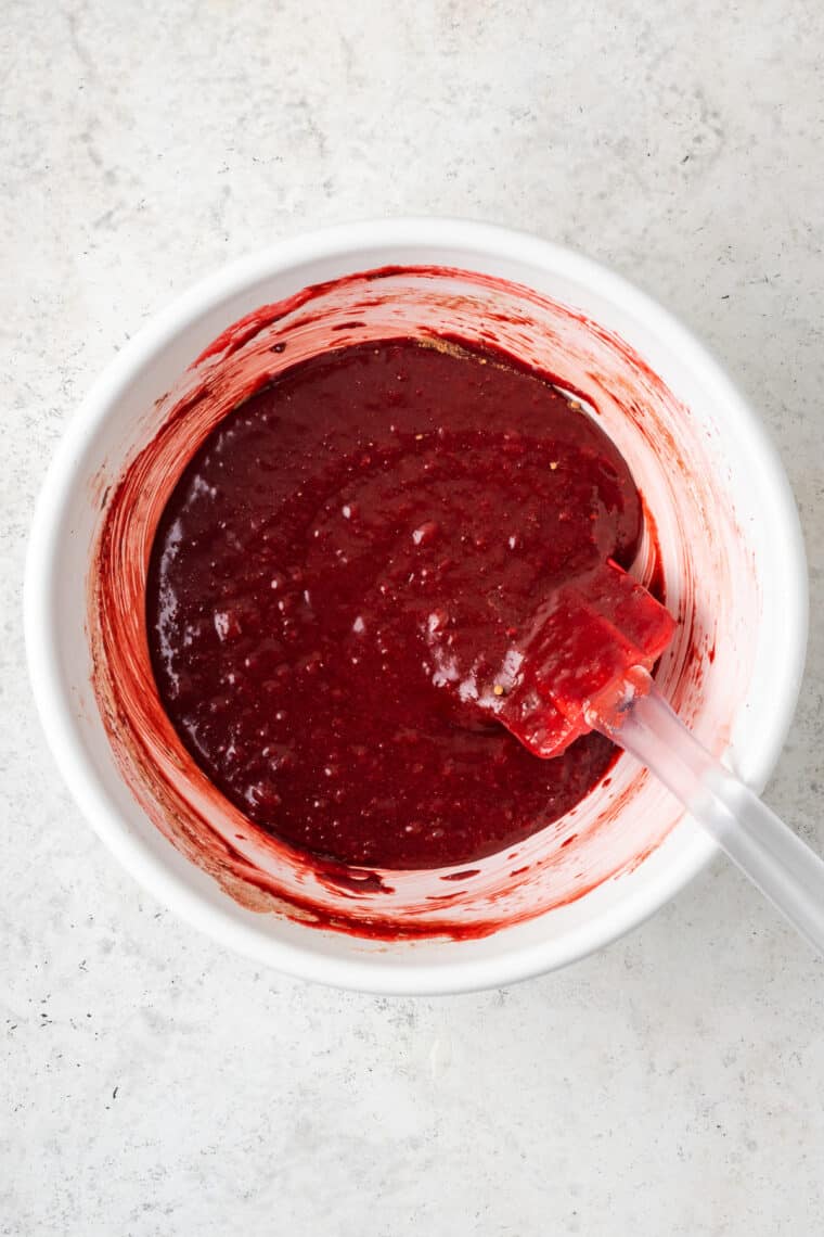 A white bowl holds red velvet brownie batter.