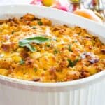 Stuffing with cheddar cheese on top in a casserole dish with text overlay that says "Gluten Free Apple Stuffing".