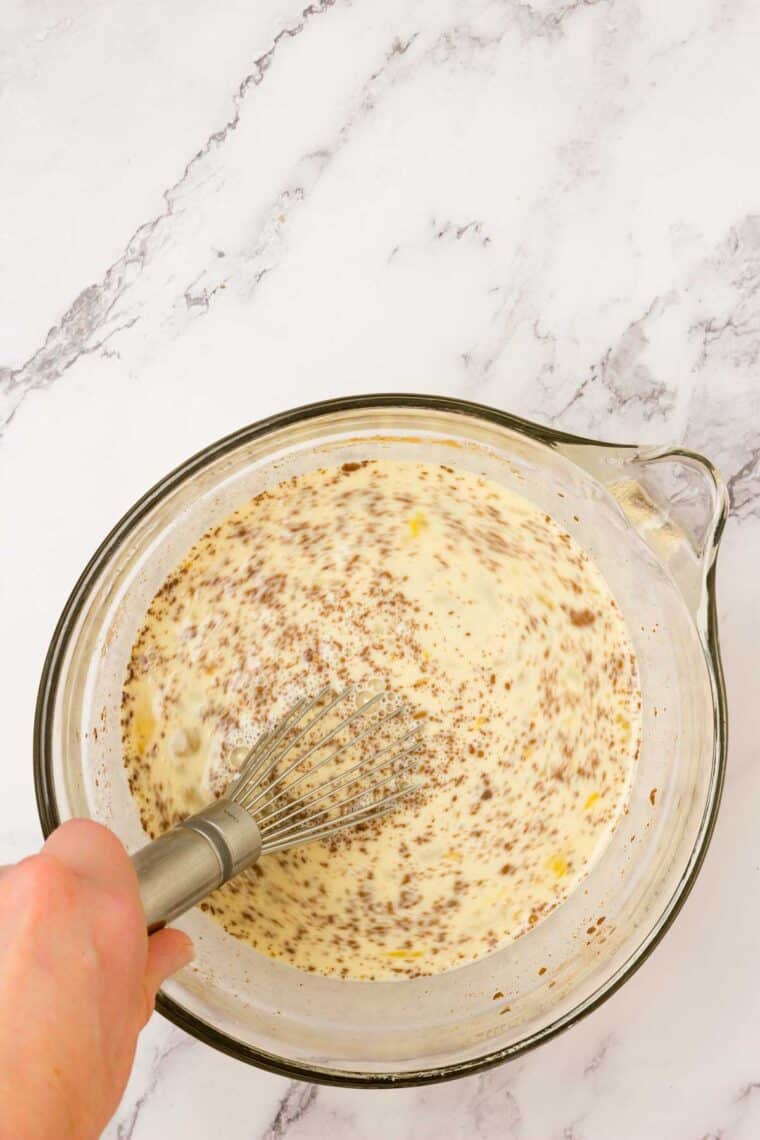A hand whisks the filling mix for French toast casserole.