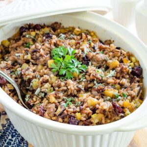Wild rice stuffing in a casserole dish with a lid leaning on it.