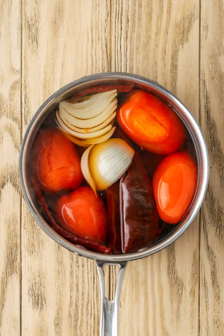 Tomatoes and onion are shown in a metal pot.