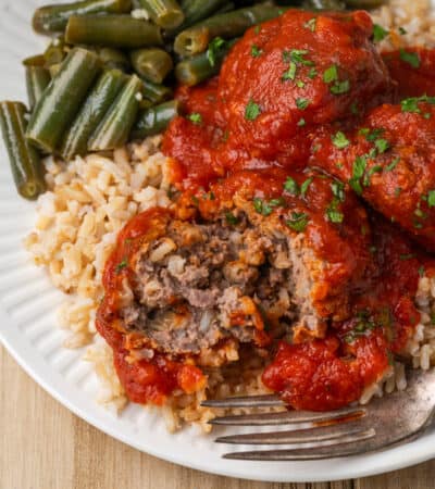 A cut meatballs shows the meaty interior, with a fork next to it.