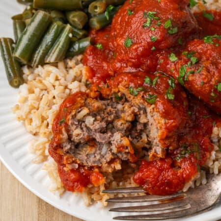 A cut meatballs shows the meaty interior, with a fork next to it.