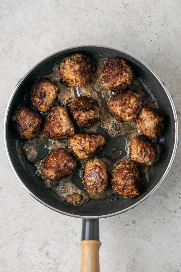 Now the meatballs are flipped and the cooked side can be seen in the skillet.