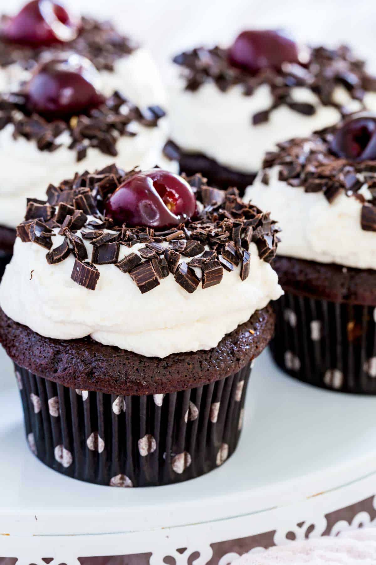 A fresh cherry sits on top of a black forest cupcake that's also garnished wtih chocolate.