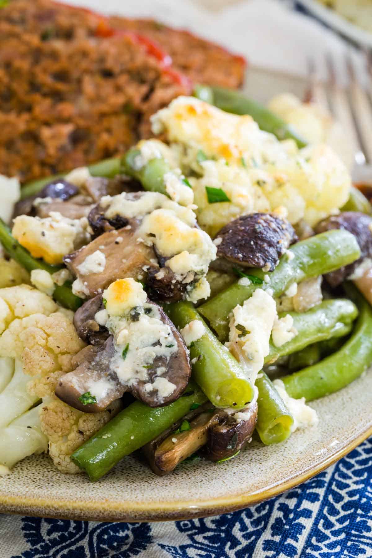 A plate of dinner includes a big portion of blue cheese roasted vegetables.
