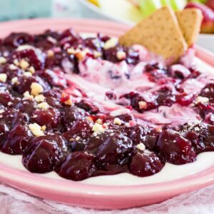 A pink dish of cherry cheesecake dip with graham crackers on the edge.