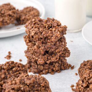 A stack of chocolate no-bake cookies with more surrounding it.