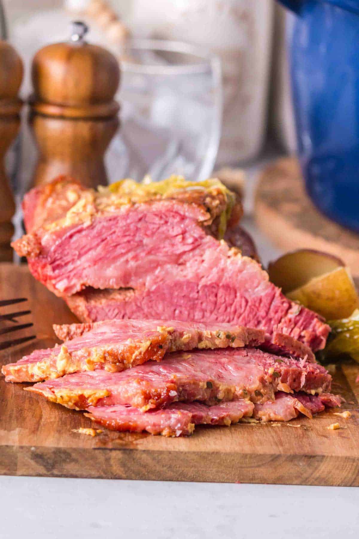 Pink slices of corned beef rest on a wooden cutting board.