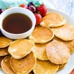 A platter of mini pancakes with a small bowl of maple syrup with text overlay that says "Gluten Free Silver Dollar Pancakes"