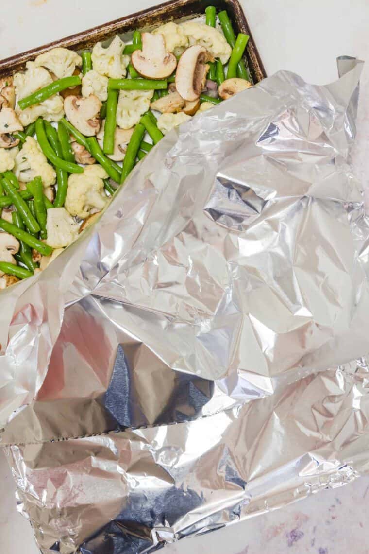Covering up the pan of vegetables with foil.