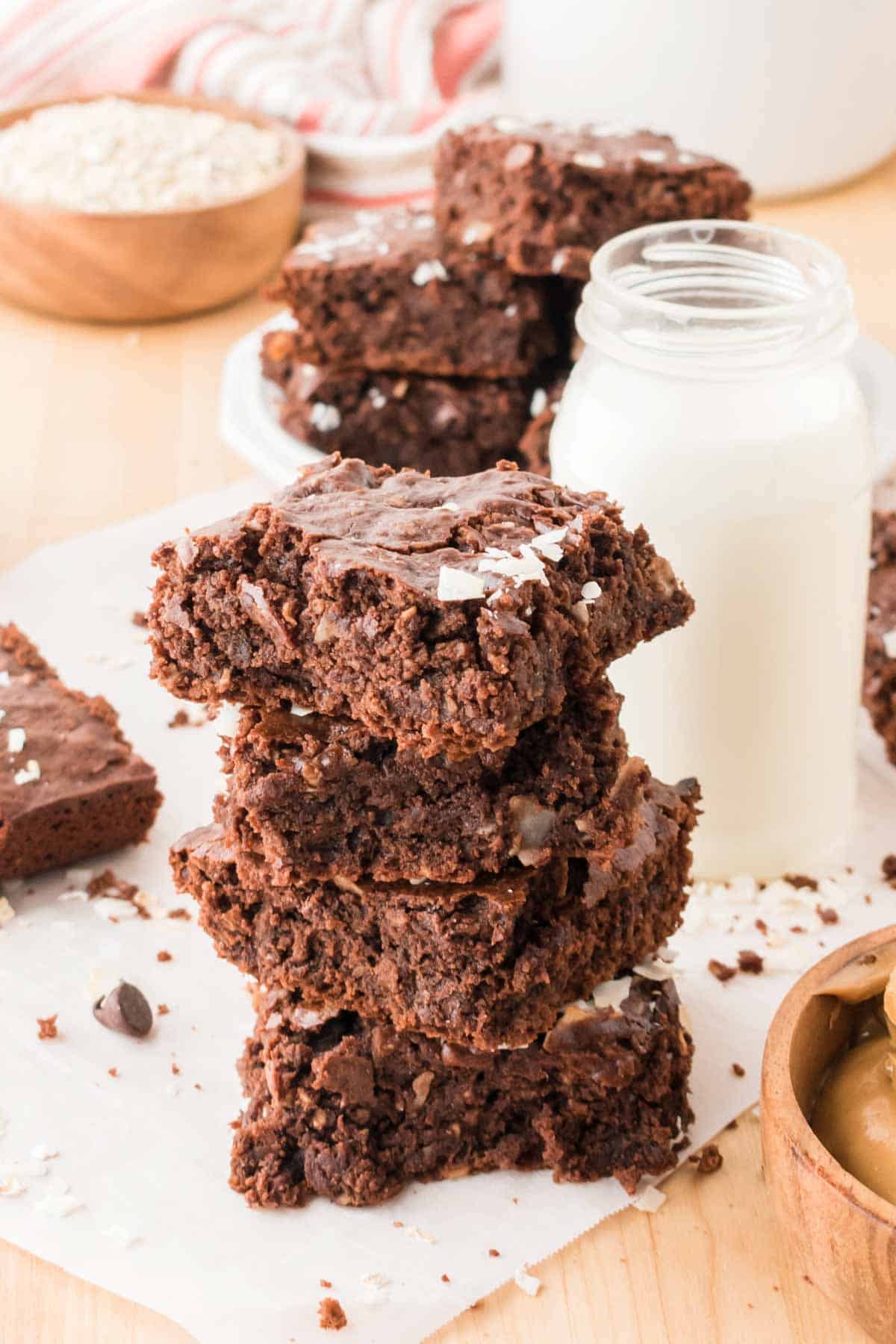 A stack gluten free protein brownies is shown next to a jar of milk.