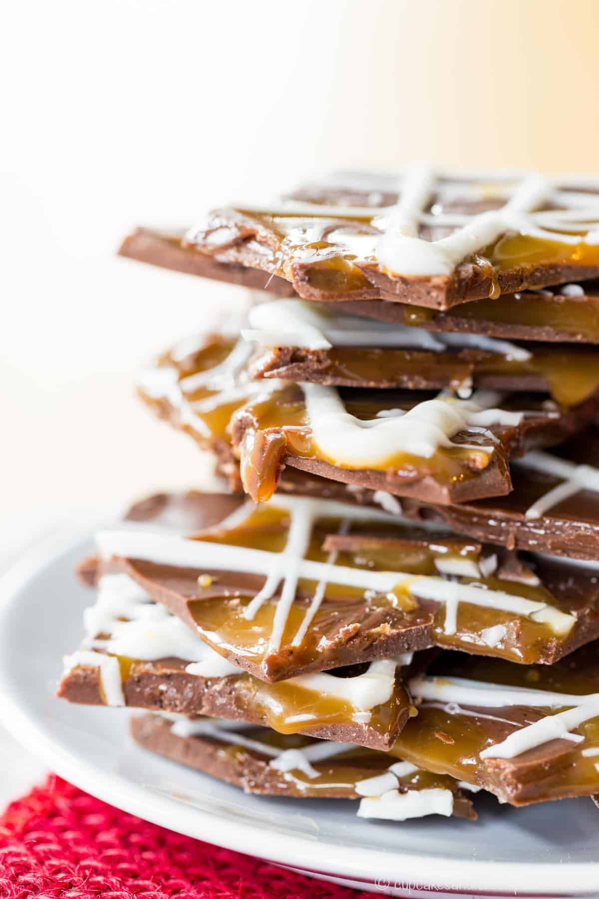 A closeup of the edges to see caramel dripping off of chocolate bark stacked on a plate.