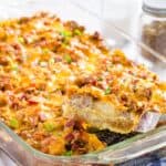 A slice of egg casserole being lifted out of a glass baking dish with a spatula with text overlay that says "Tater Tot Breakfast Casserole".