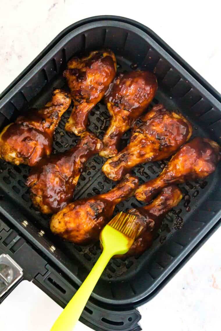 BBQ sauce is brushed on air fryer bbq chicken legs as they cook in the air fryer.