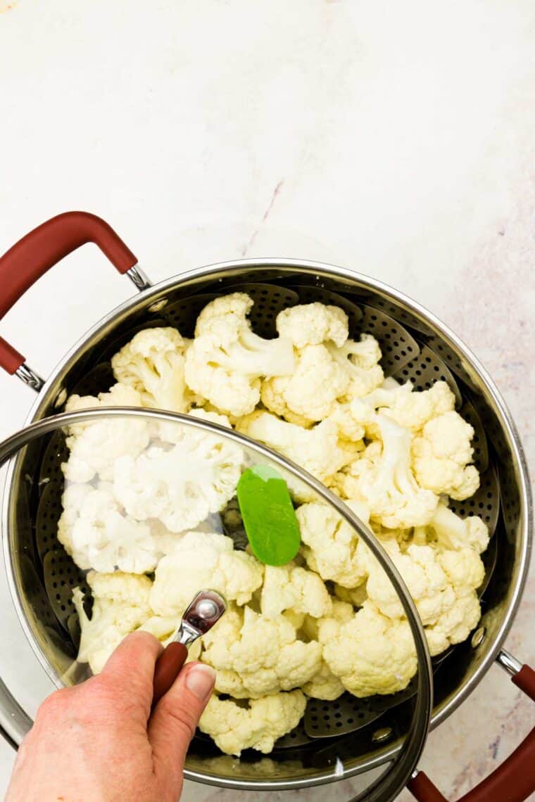 A clear lid is placed on a pot of cauliflower.